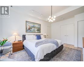 A bedroom with a large bed and a painting on the wall.
