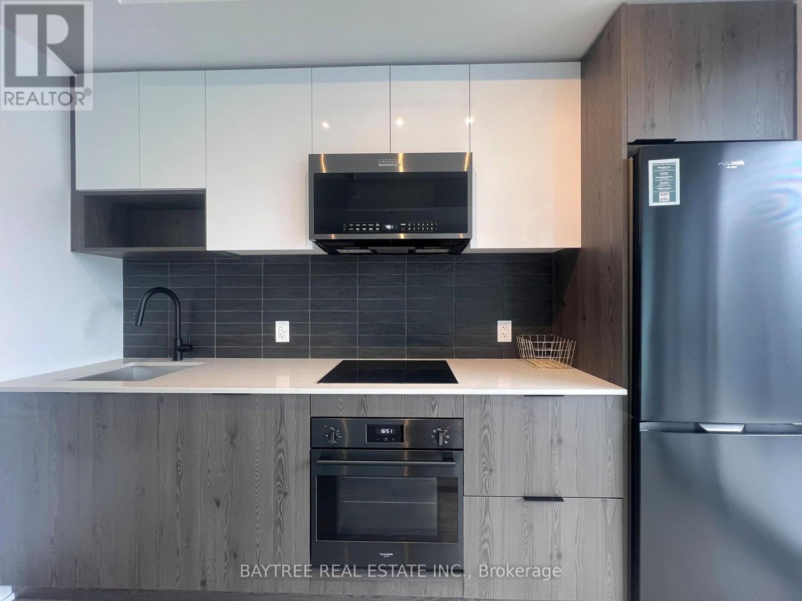 A modern kitchen with a stainless steel refrigerator and wooden cabinets.