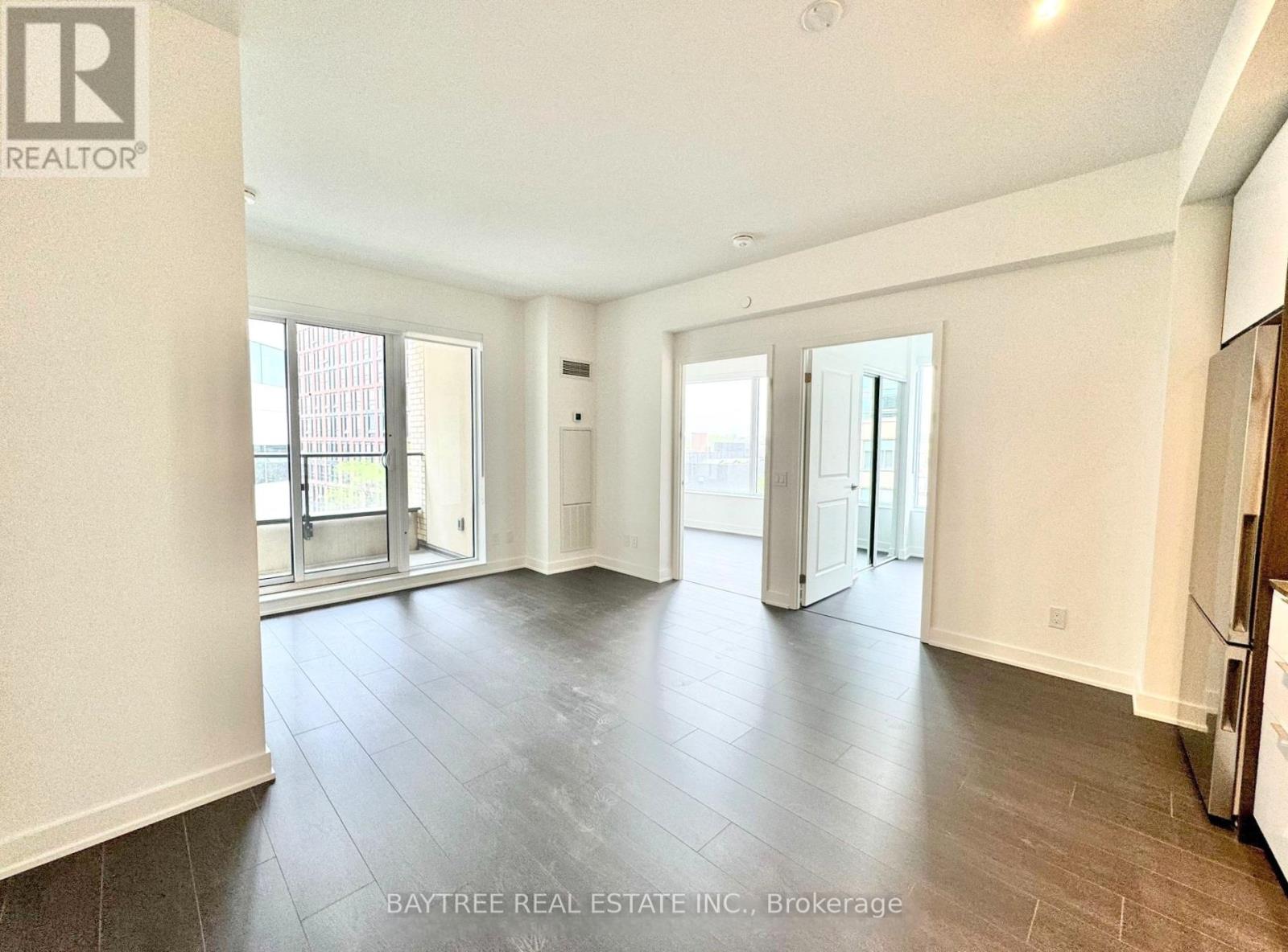 A spacious living room with a bay window and hardwood flooring.