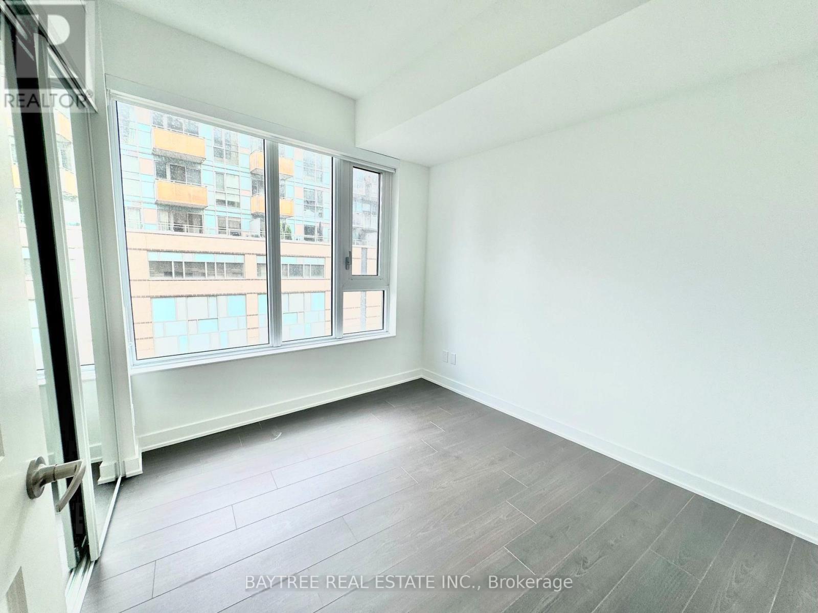A room with a large window and a view of a building across the street.