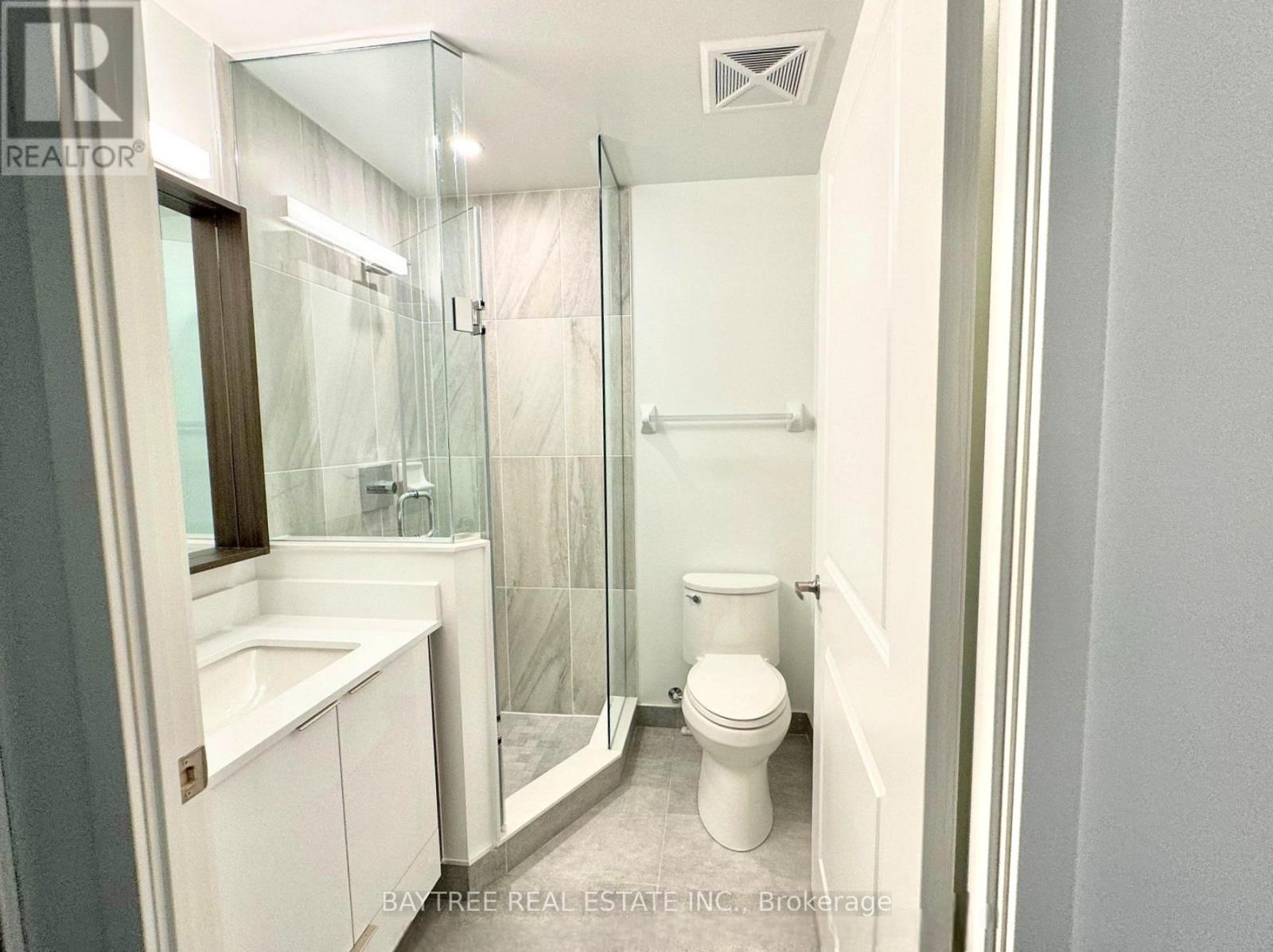 A white bathroom with a toilet, sink, and shower.