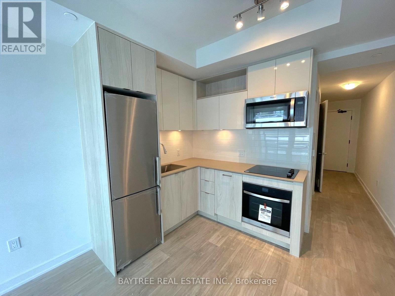 A kitchen with a refrigerator, microwave, and oven.