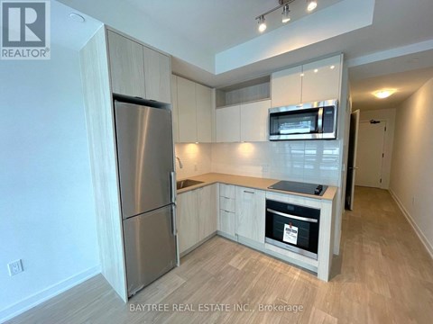 A kitchen with a refrigerator, microwave, and oven.