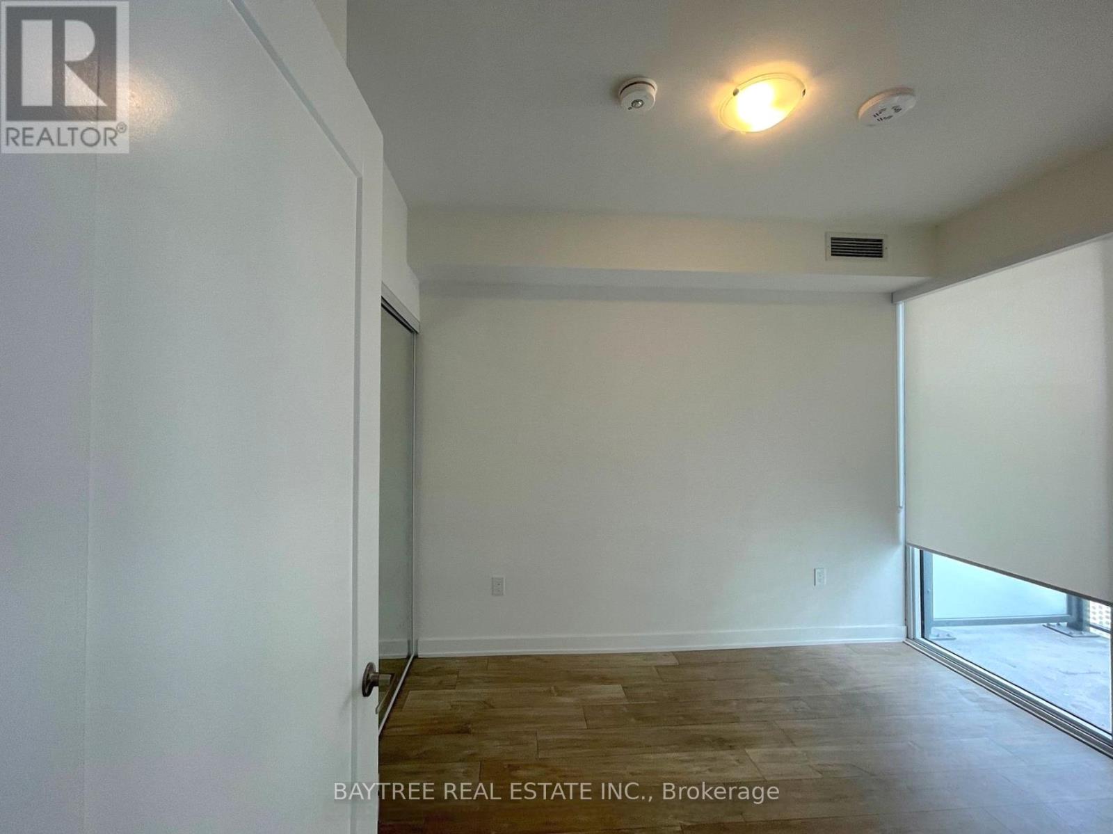 A room with a wooden floor and white walls, with a window on the right side.