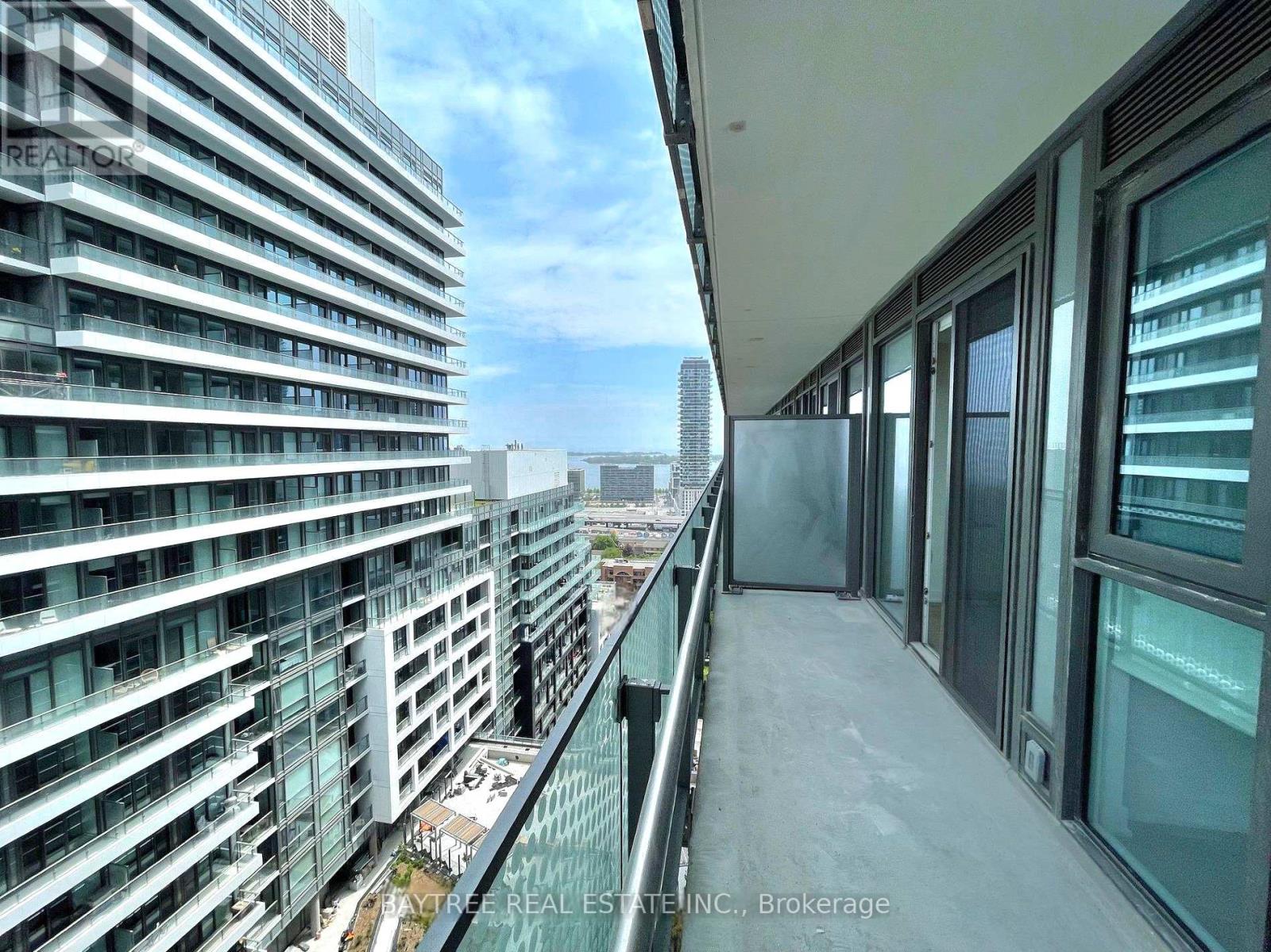 A balcony of a building with glass railings and a view of the city.
