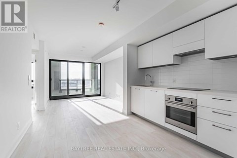 A modern kitchen with white cabinets and a large window.