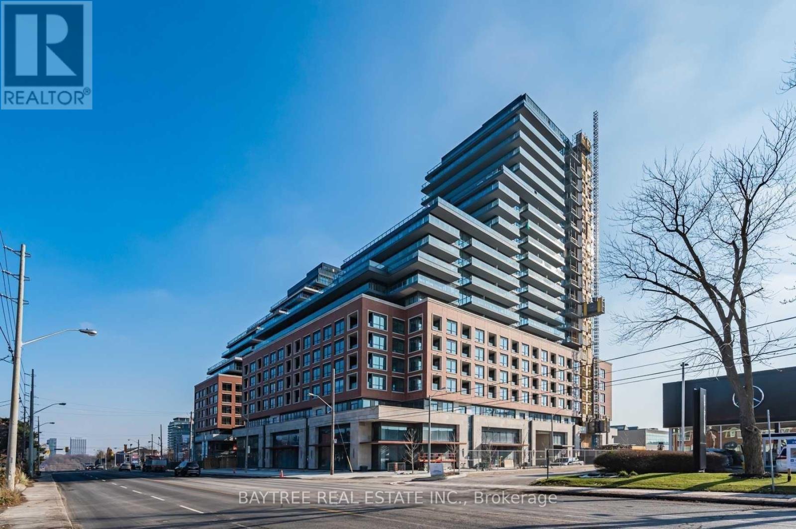 A modern multi-story building with a glass facade is under construction.