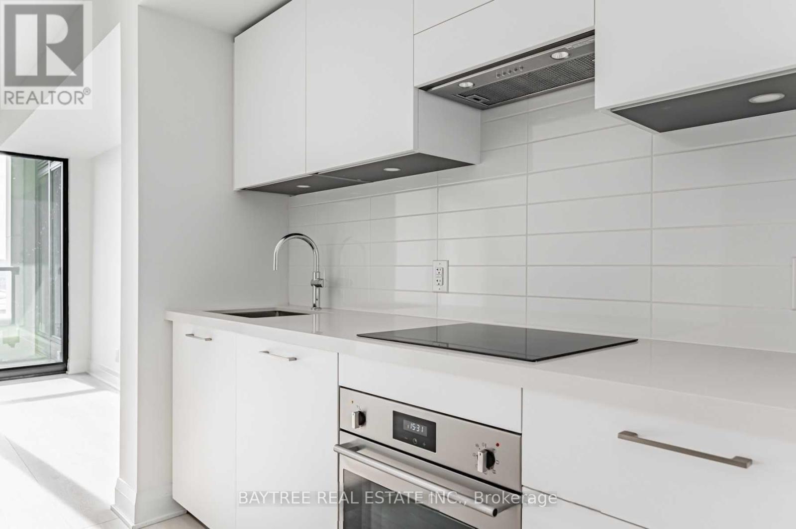 A modern kitchen with white cabinets and a black countertop.