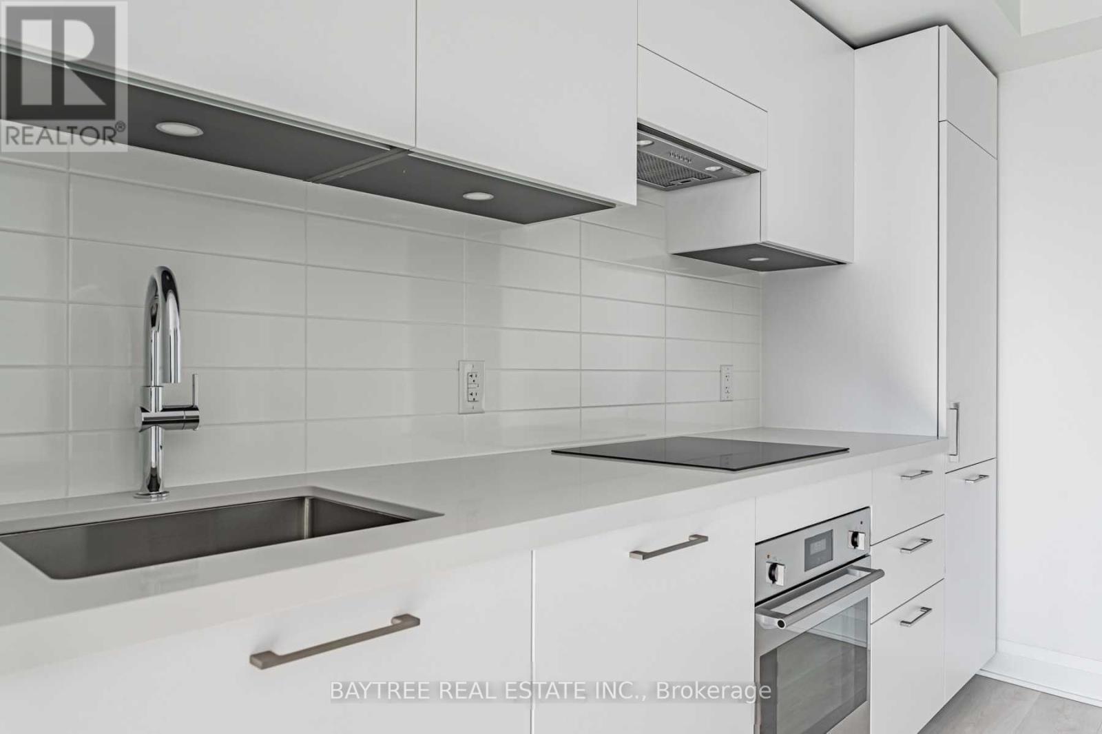 A modern kitchen with white cabinets and stainless steel appliances.
