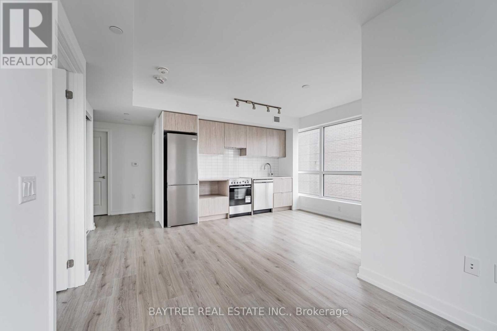 A spacious kitchen with white walls and wooden flooring.