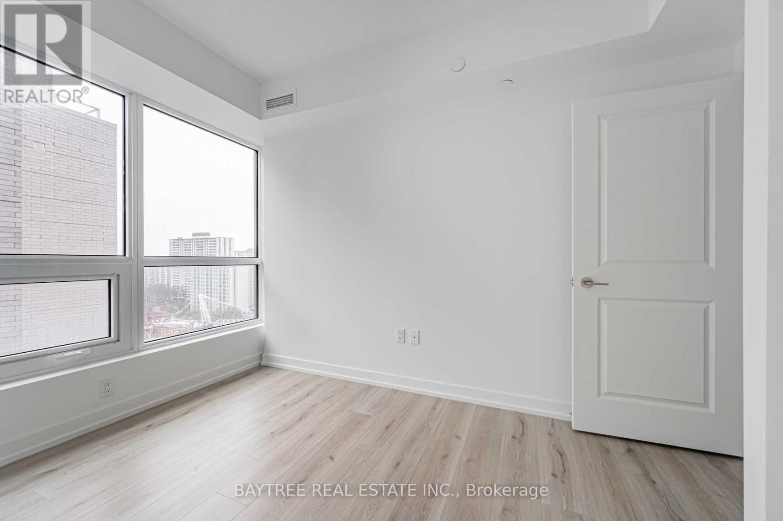 A room with a door and a window with a view of buildings outside.