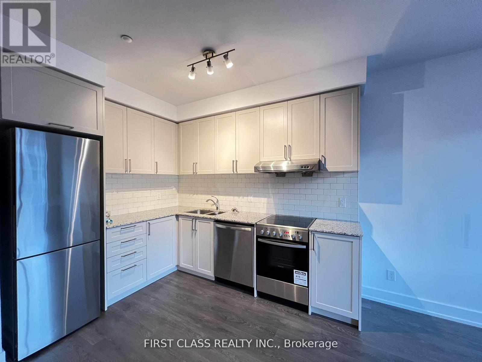 A modern kitchen with a stainless steel refrigerator and white cabinets.