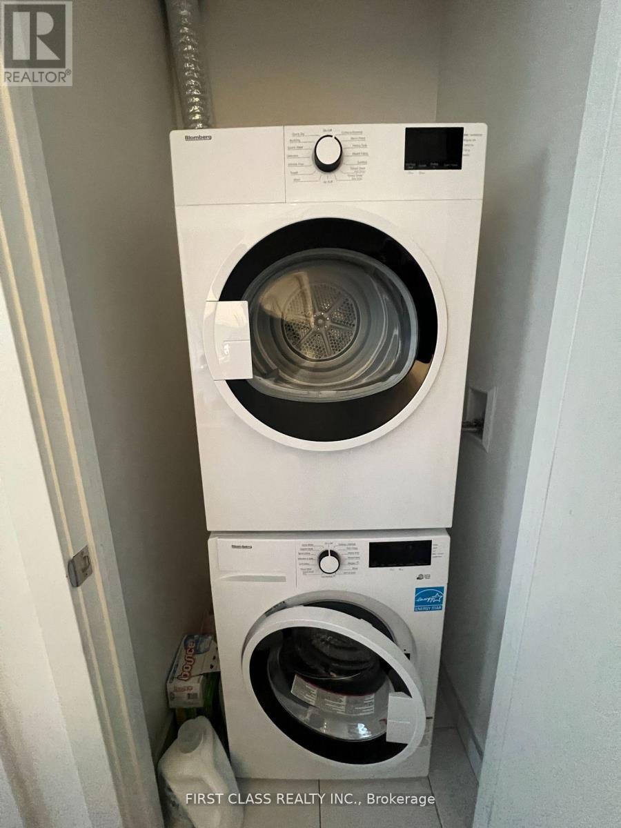 A white washing machine is stacked on top of another white washing machine.