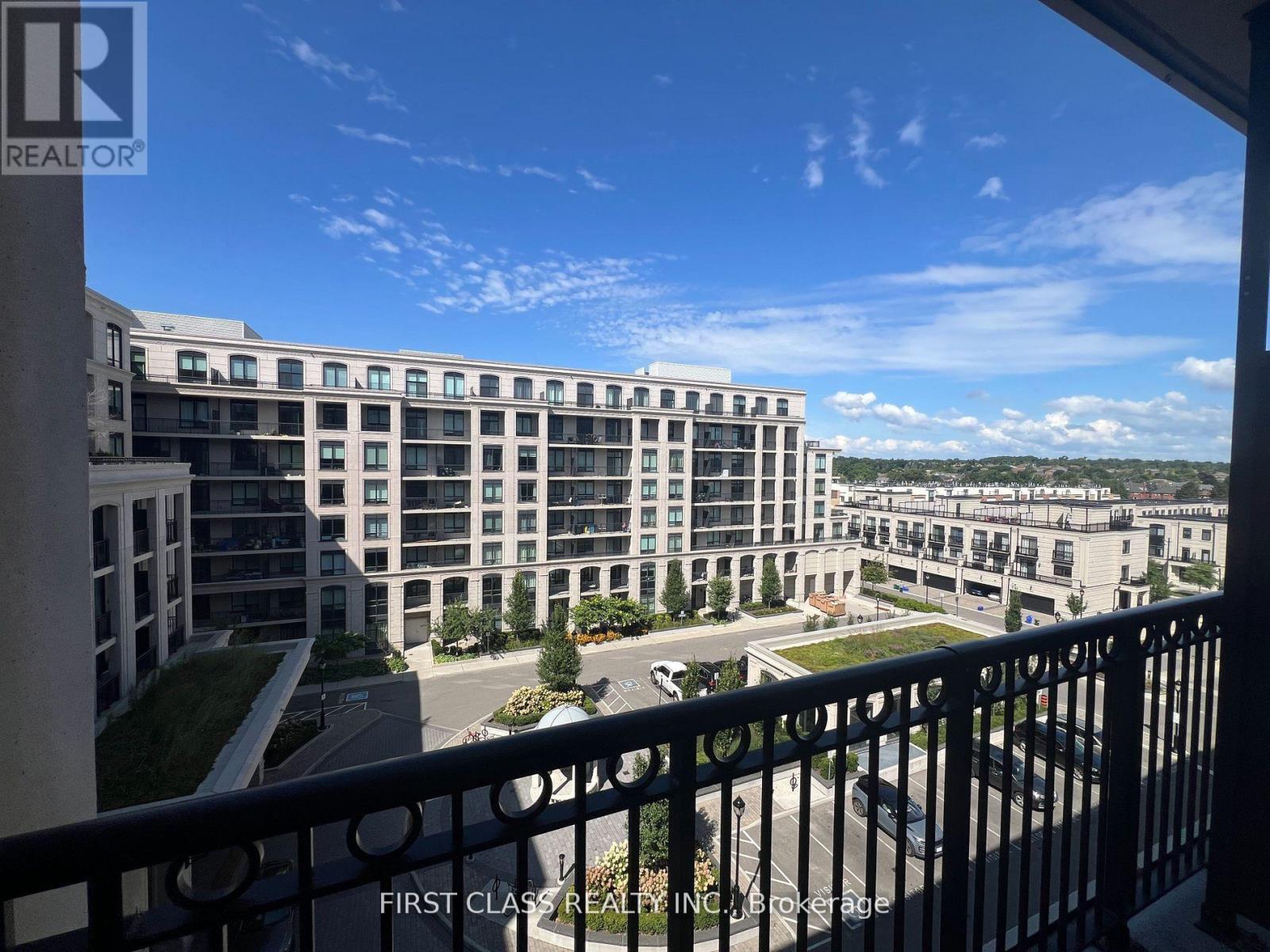 A balcony overlooks a parking lot and apartment buildings.