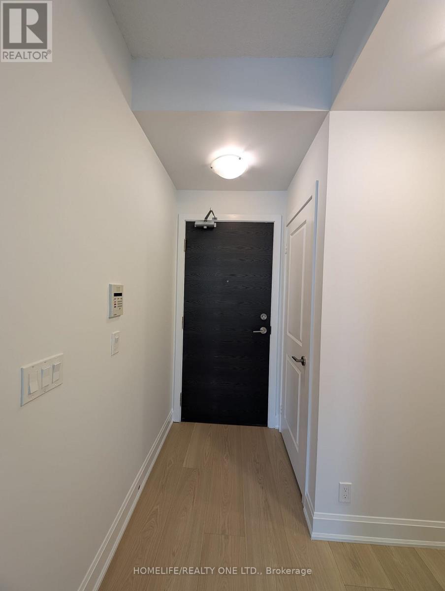 A black door is at the end of a hallway with white walls.
