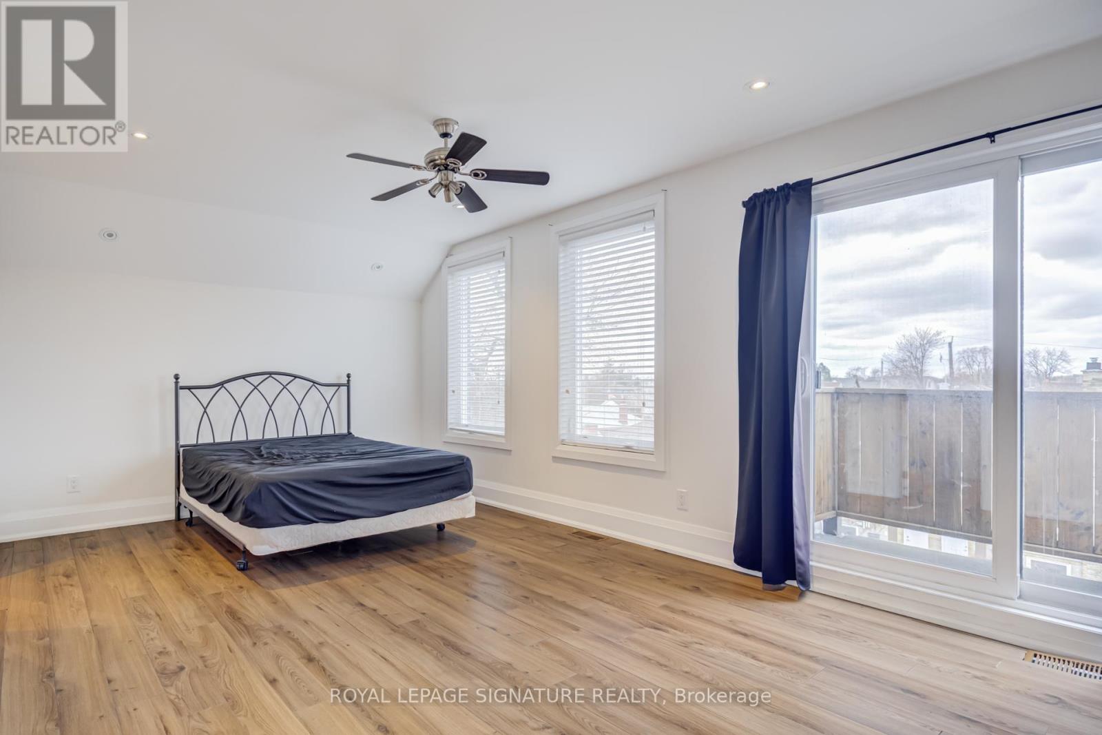 A bedroom with a bed, a ceiling fan, and a sliding glass door.