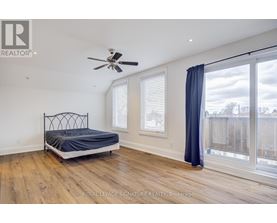 A bedroom with a bed, a ceiling fan, and a sliding glass door.