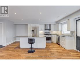 A modern kitchen with a bar stool in the middle.