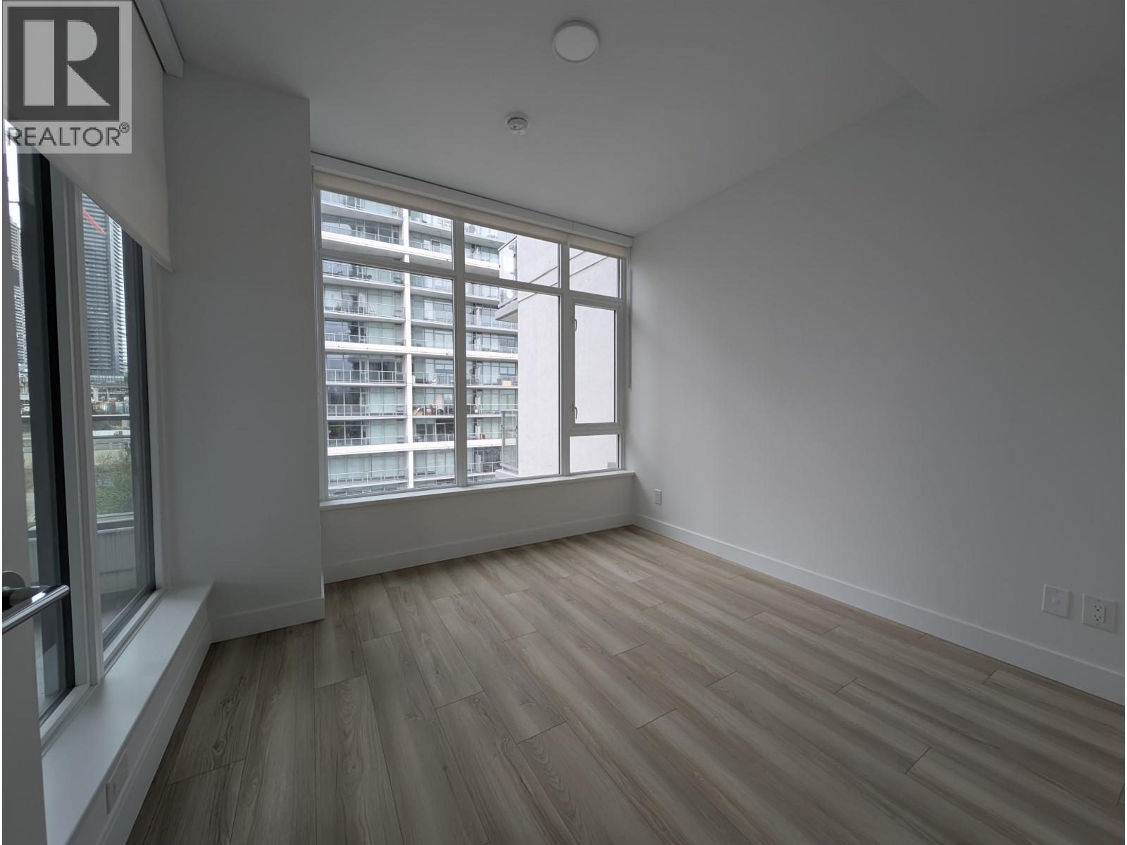 A room with a window overlooking a building with the logo REALTOR on the top left.