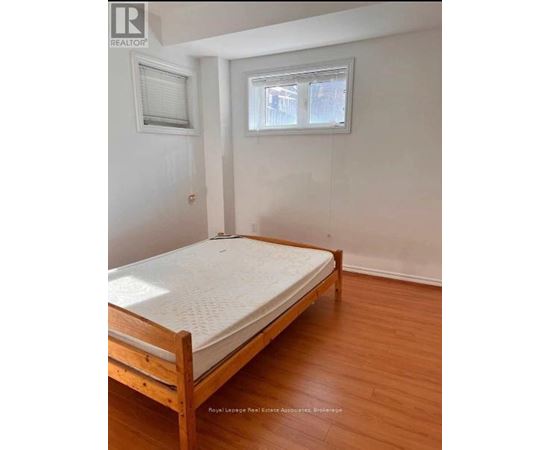 A bedroom with a bed, wooden floors, and two windows.