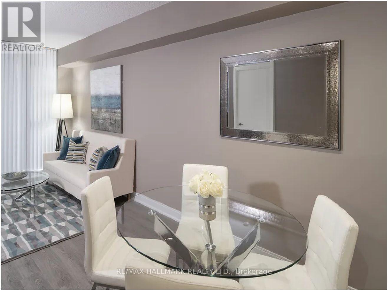 A modern dining room with a glass table and white chairs.