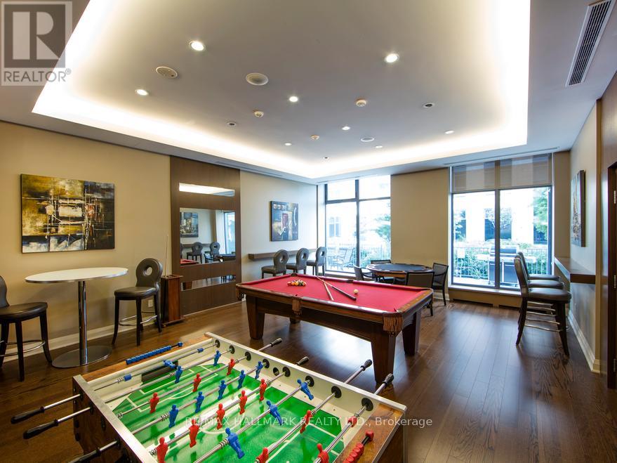 A foosball table is in the middle of a room with a pool table and a couch.