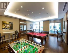 A foosball table is in the middle of a room with a pool table and a couch.
