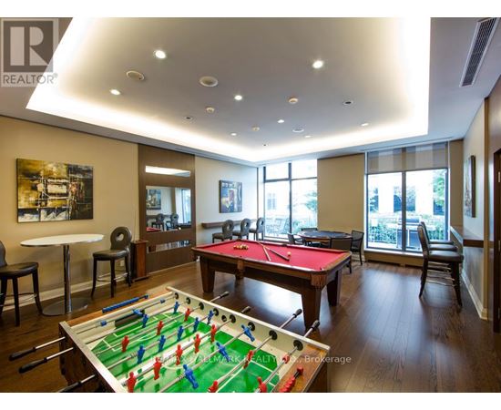 A foosball table is in the middle of a room with a pool table and a couch.