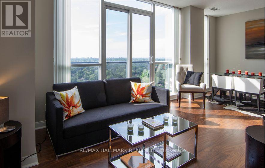 A living room with a black couch and a glass coffee table.
