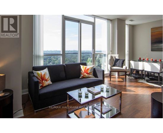 A living room with a black couch and a glass coffee table.