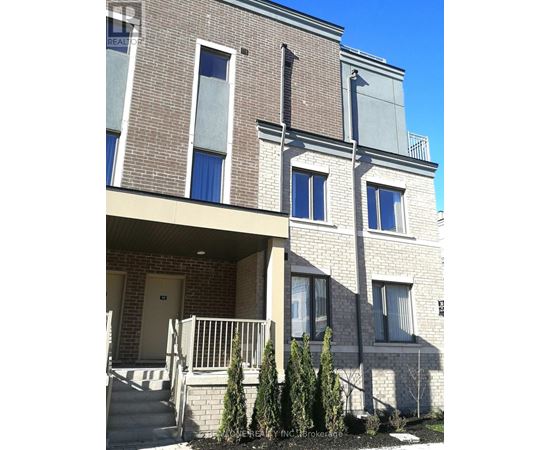 A two-story brick building with a balcony and a small garden in front.