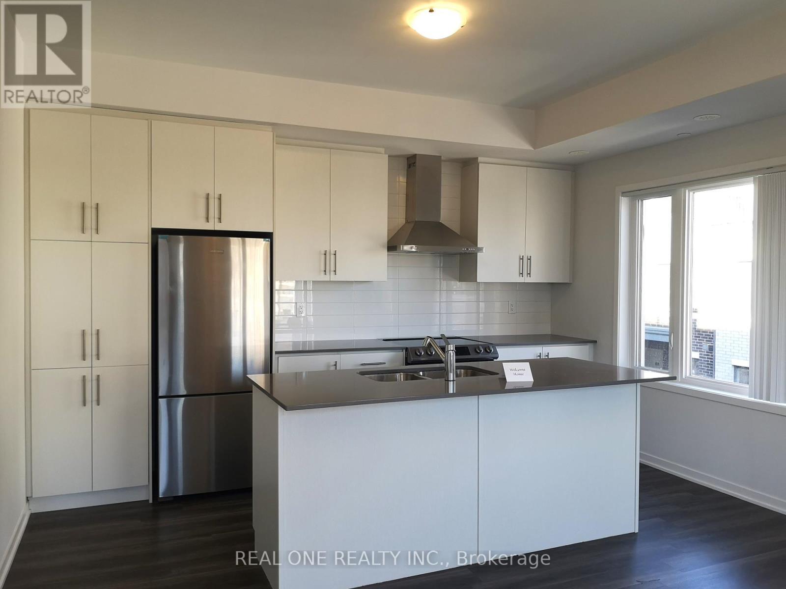 A kitchen with white cabinets and a stainless steel refrigerator.
