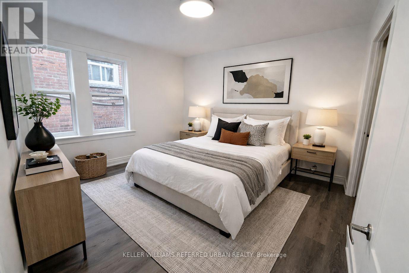 A bedroom with a large bed, a nightstand, and a window.
