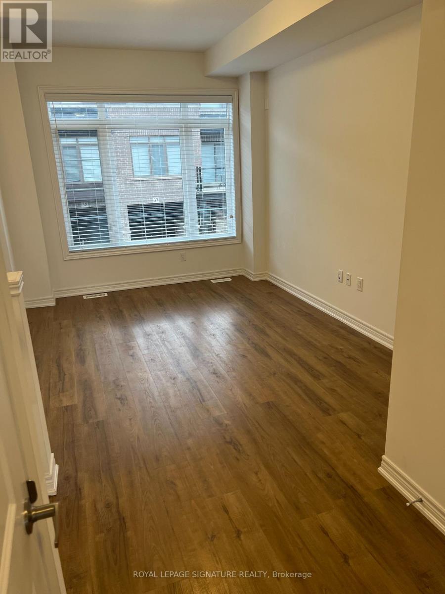 A room with wooden flooring and a window showing a building outside.