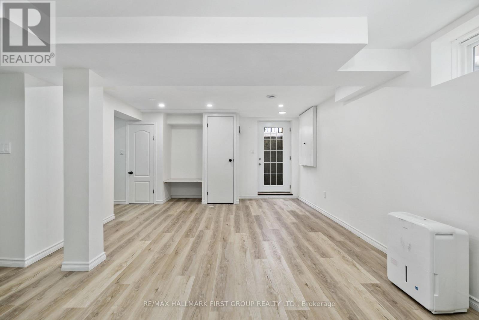 A spacious room with wooden flooring and white walls.