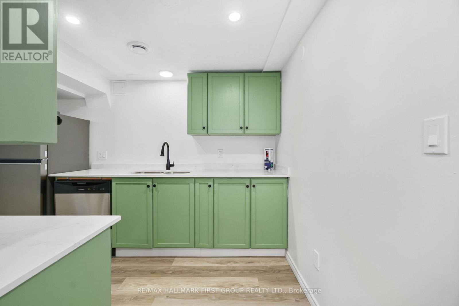 A kitchen with green cabinets and a white counter.