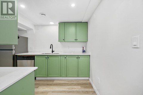 A kitchen with green cabinets and a white counter.