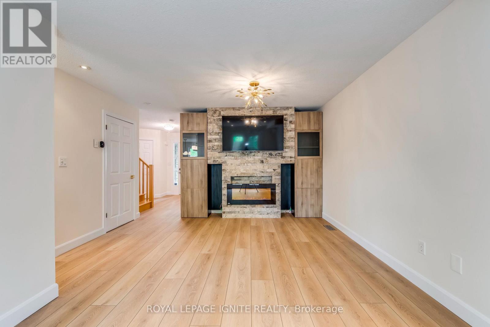 A spacious living room with a stone fireplace and a flat screen TV mounted above it.