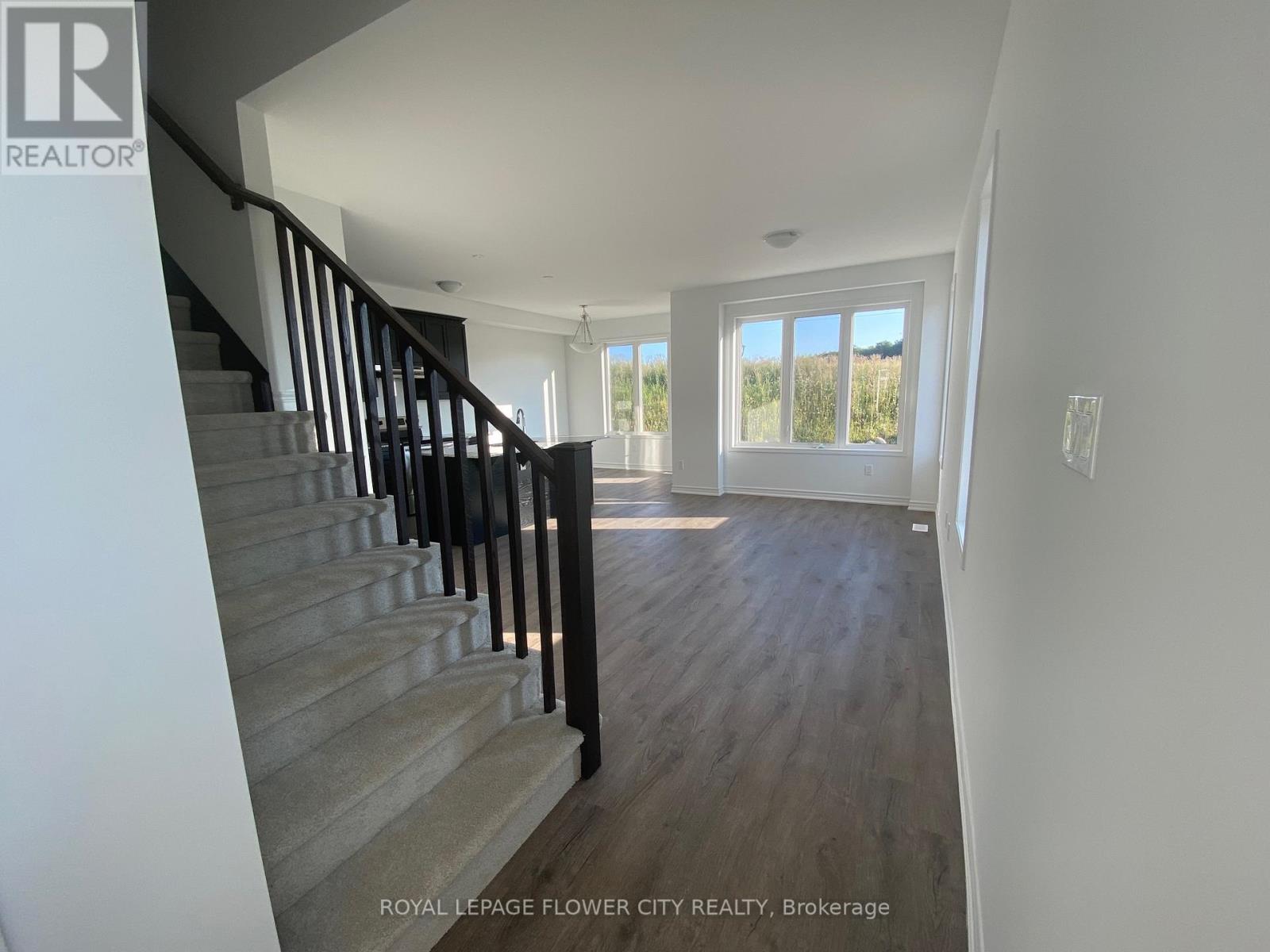 A staircase with a black railing leads to a bright room with a large window.