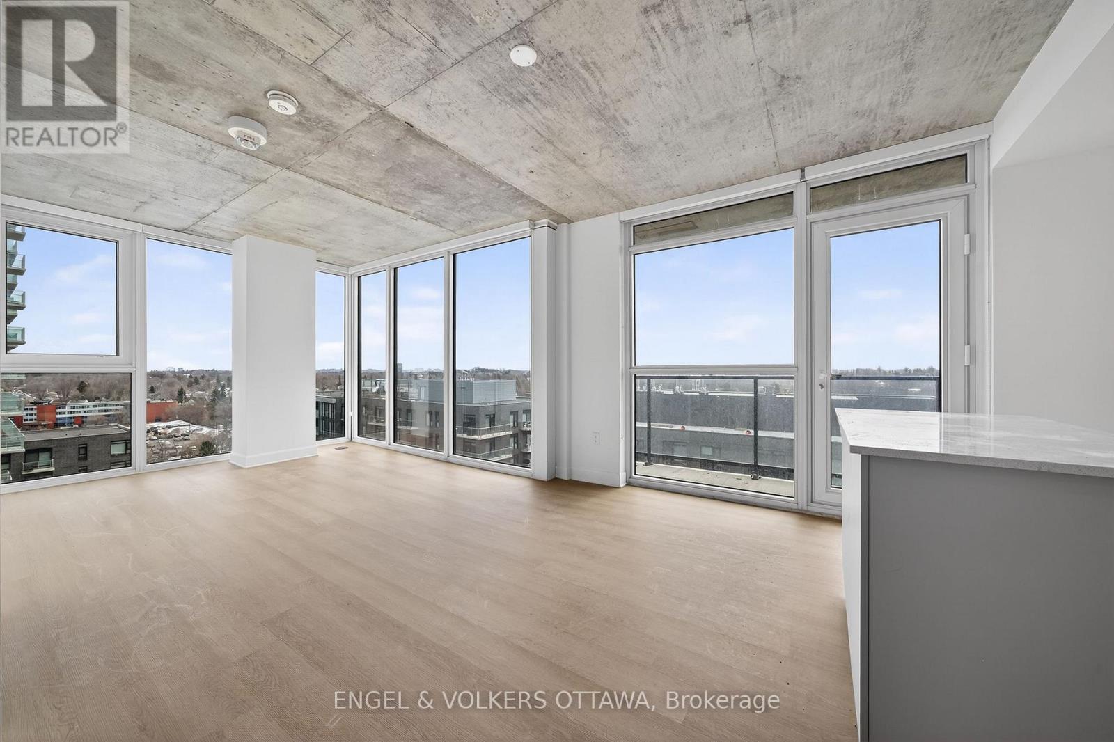 A large, empty room with a view of the cityscape outside the windows.