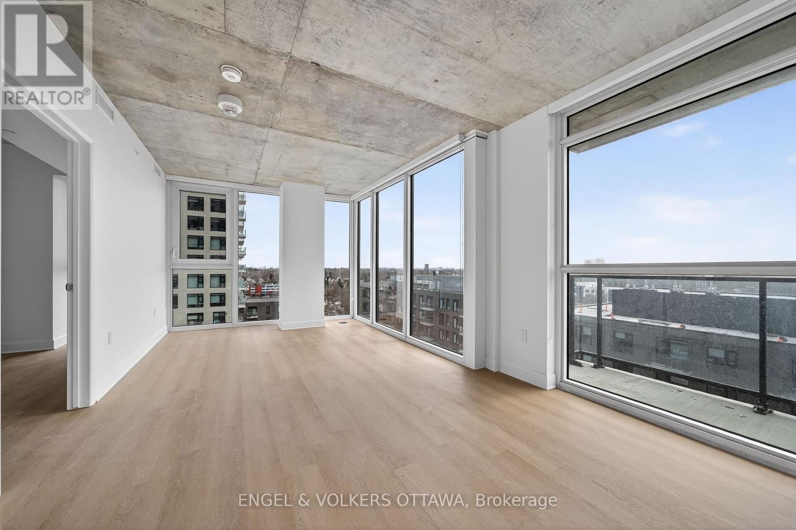 A large, empty room with a view of the cityscape outside the windows.