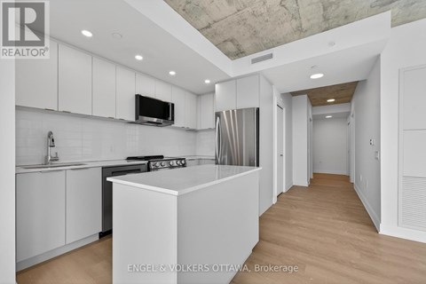 A modern kitchen with white cabinets and a wooden floor.