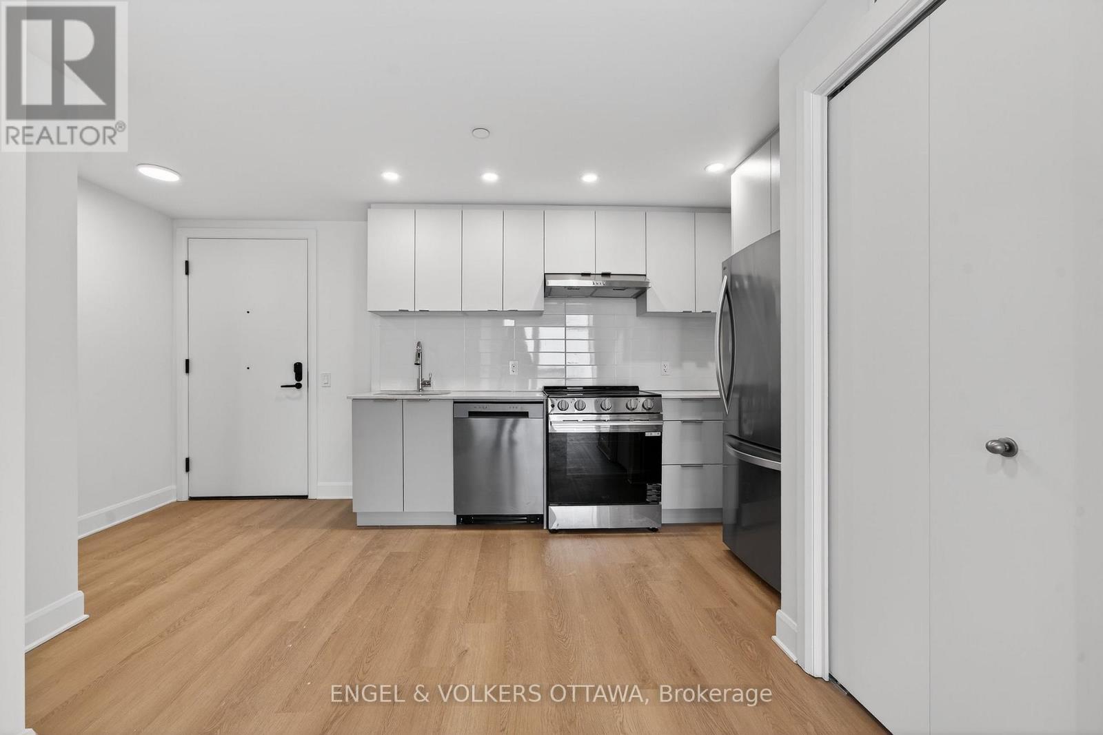 A modern kitchen with wooden floors and stainless steel appliances.
