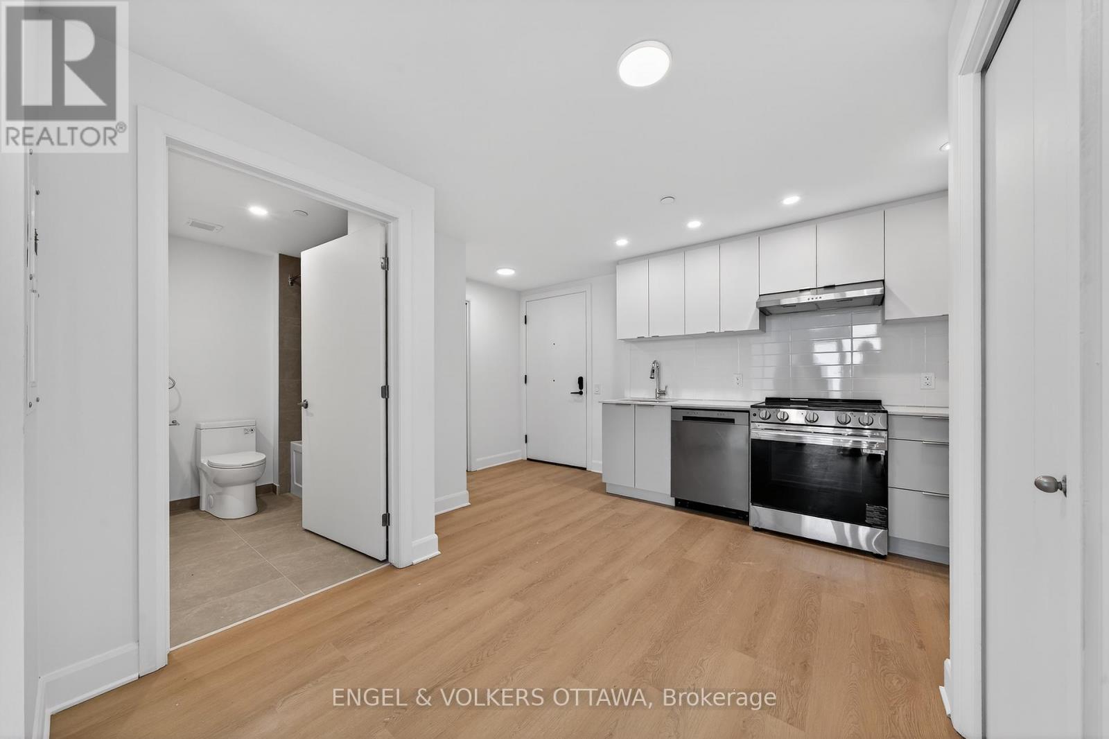A white kitchen with wooden floors and a stainless steel oven.
