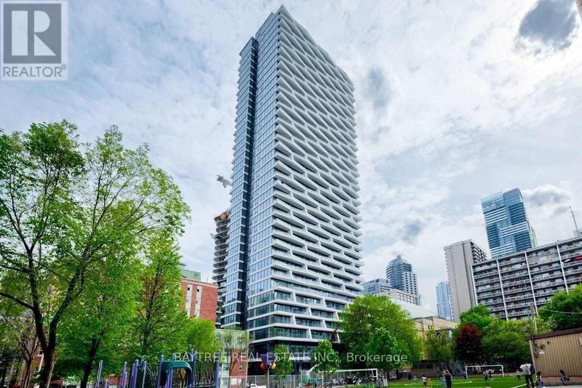 A tall building with a glass facade stands in the foreground of a cityscape.