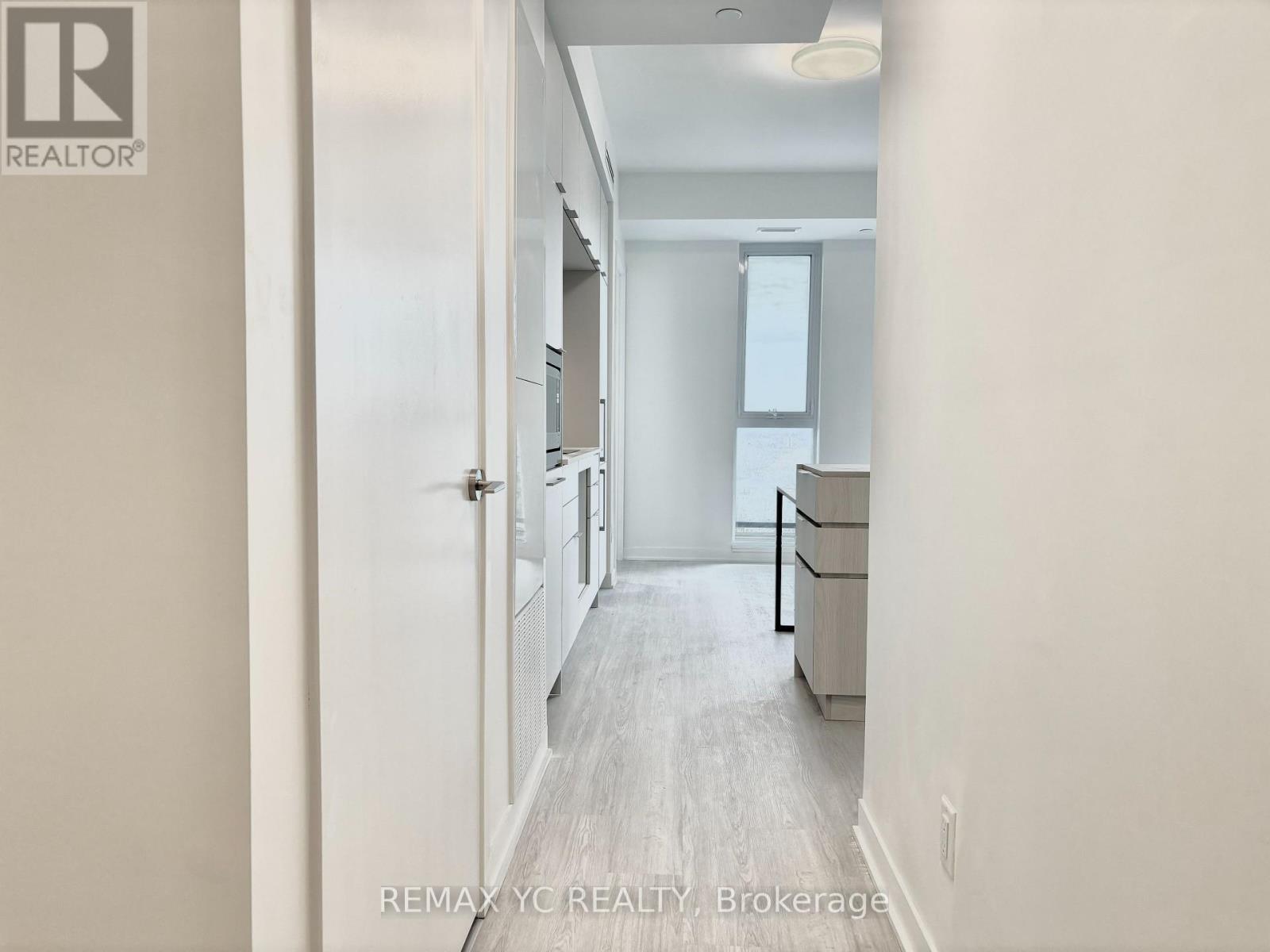 A hallway with a door on the left and a window on the right.