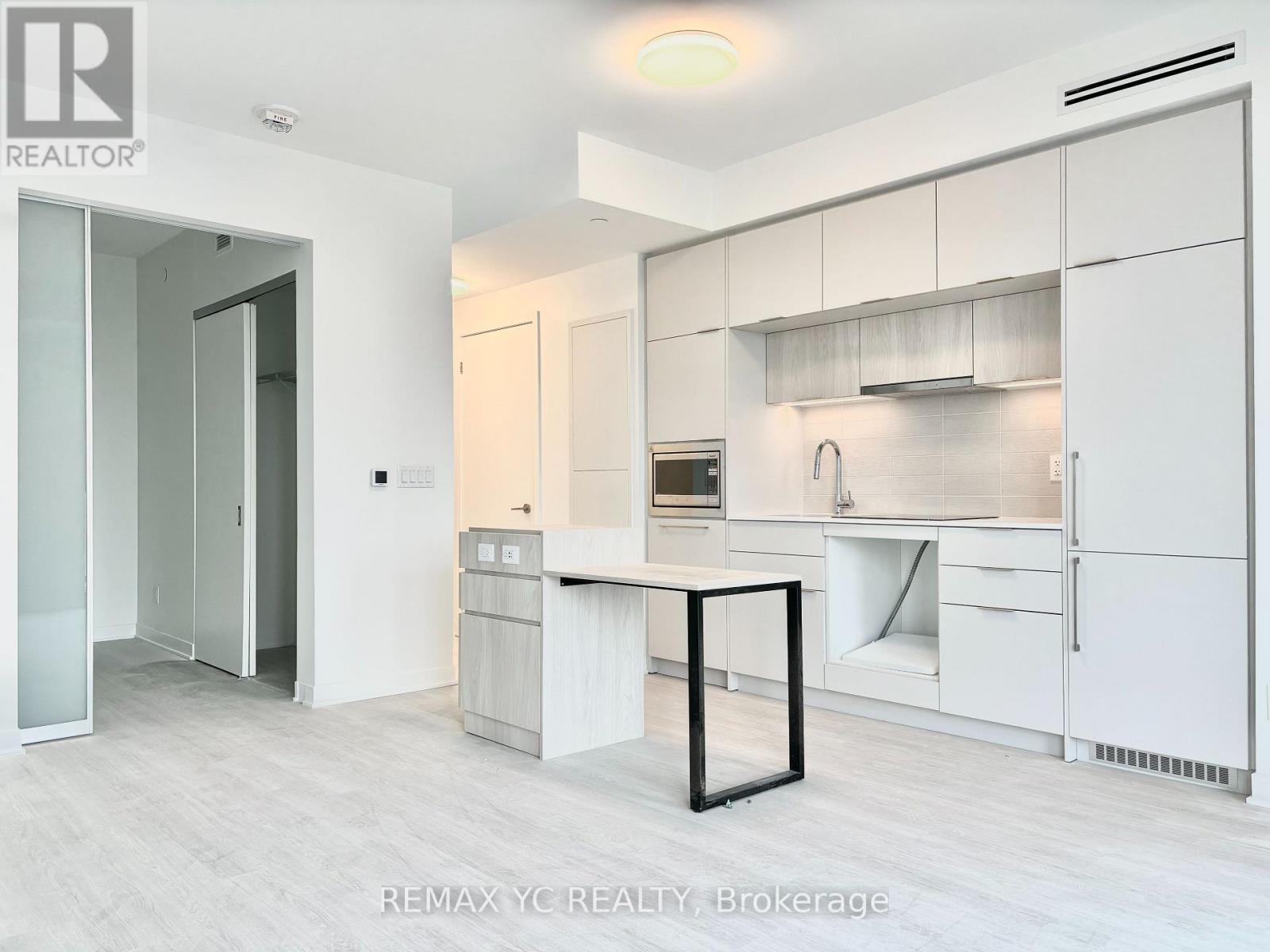 A white kitchen with a table and a fridge.