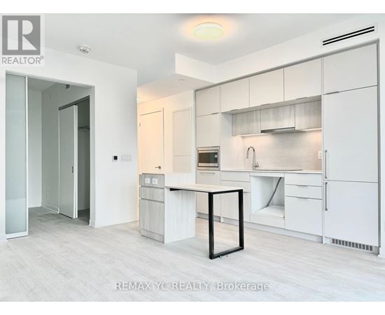 A white kitchen with a table and a fridge.