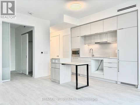 A white kitchen with a table and a fridge.