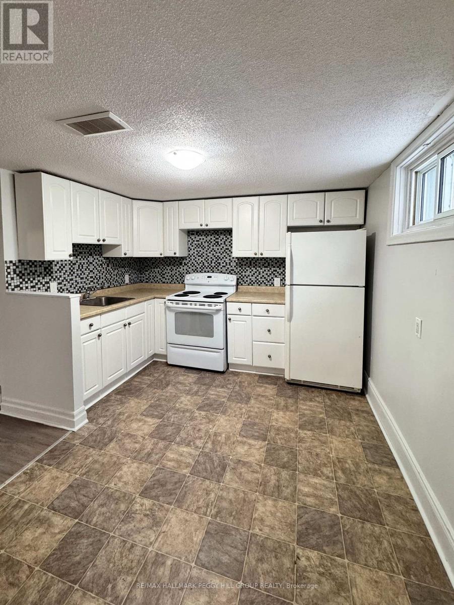 A kitchen with white appliances and brown tiled flooring.